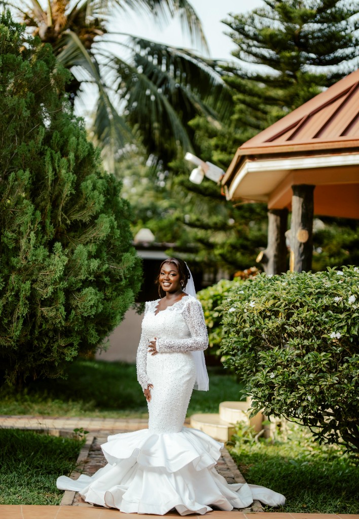 Full-length bridal portrait in white lace mermaid gown, outdoor garden